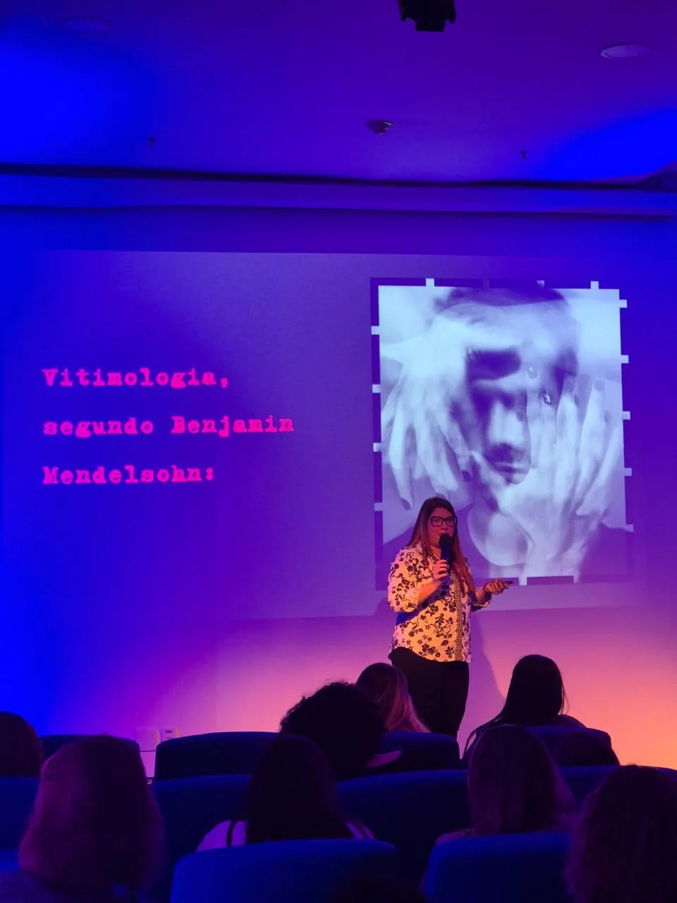 Michelle Santiago no palco, em palestra sobre vitimologia